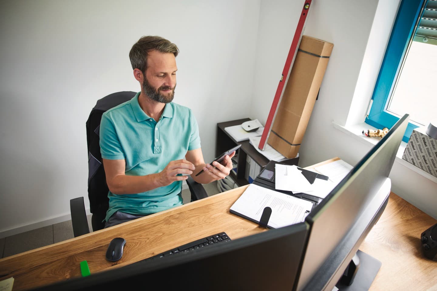 Man zit aan zijn bureau en kijkt naar smartphone